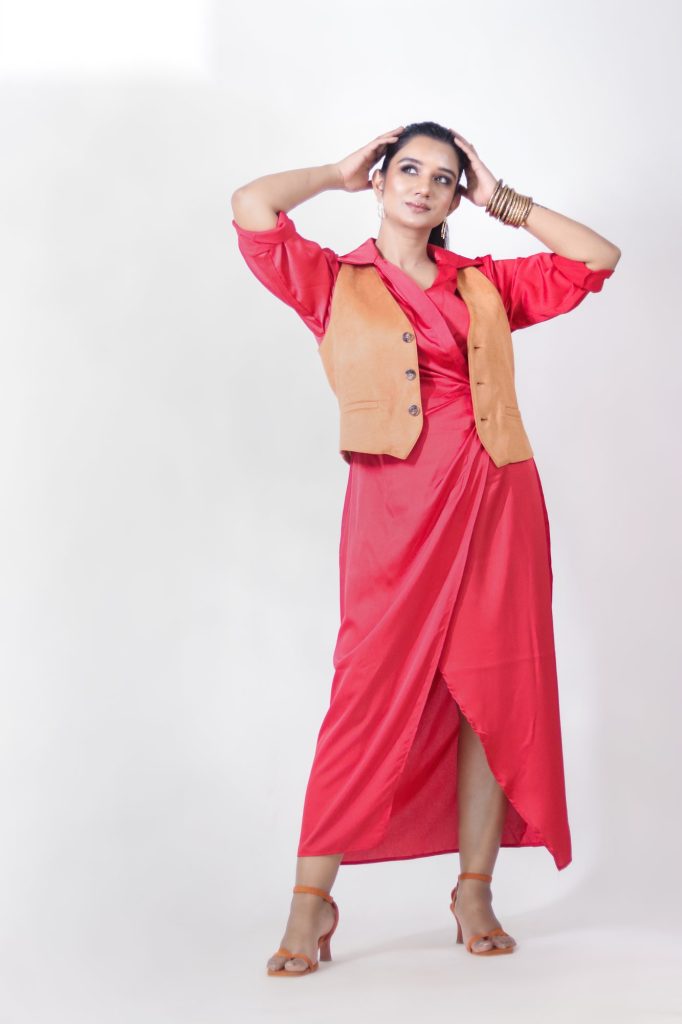 Sakshi Jethwani styling a red dress with a tan waistcoat